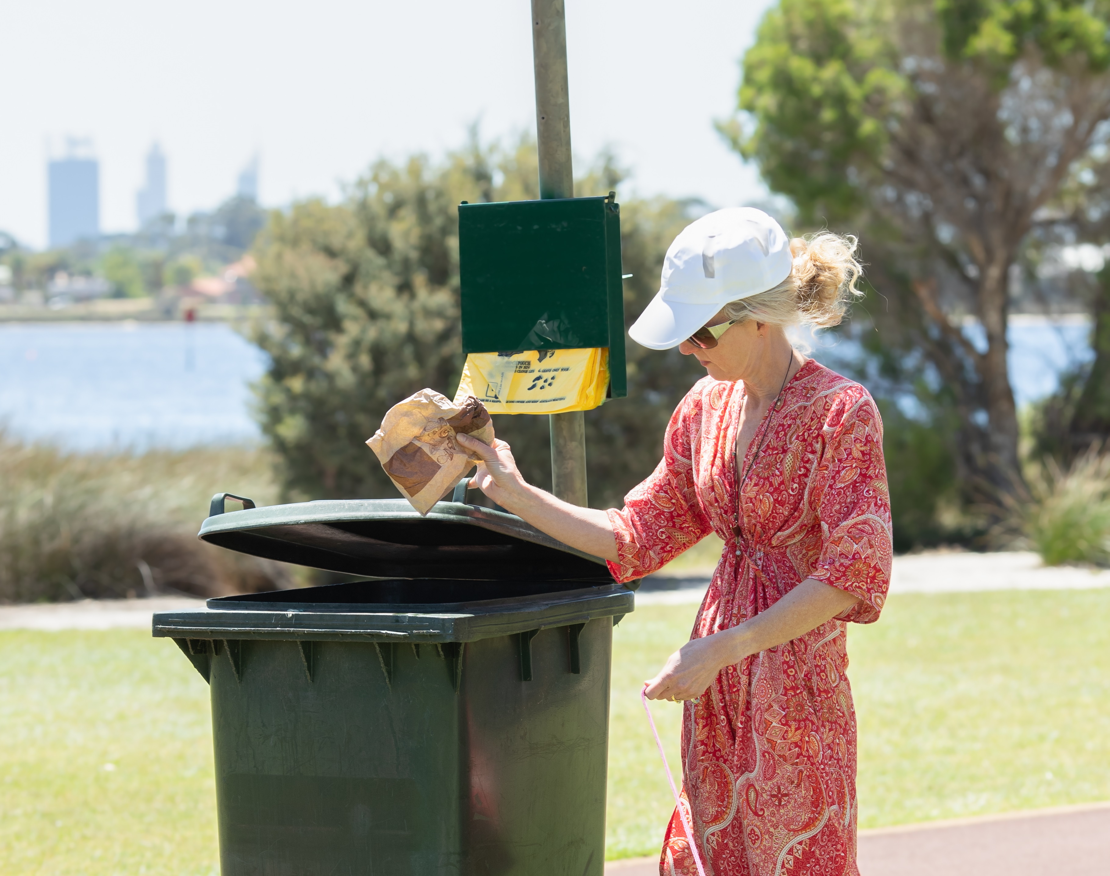 Woman putting rubbish in bin at a dog park.